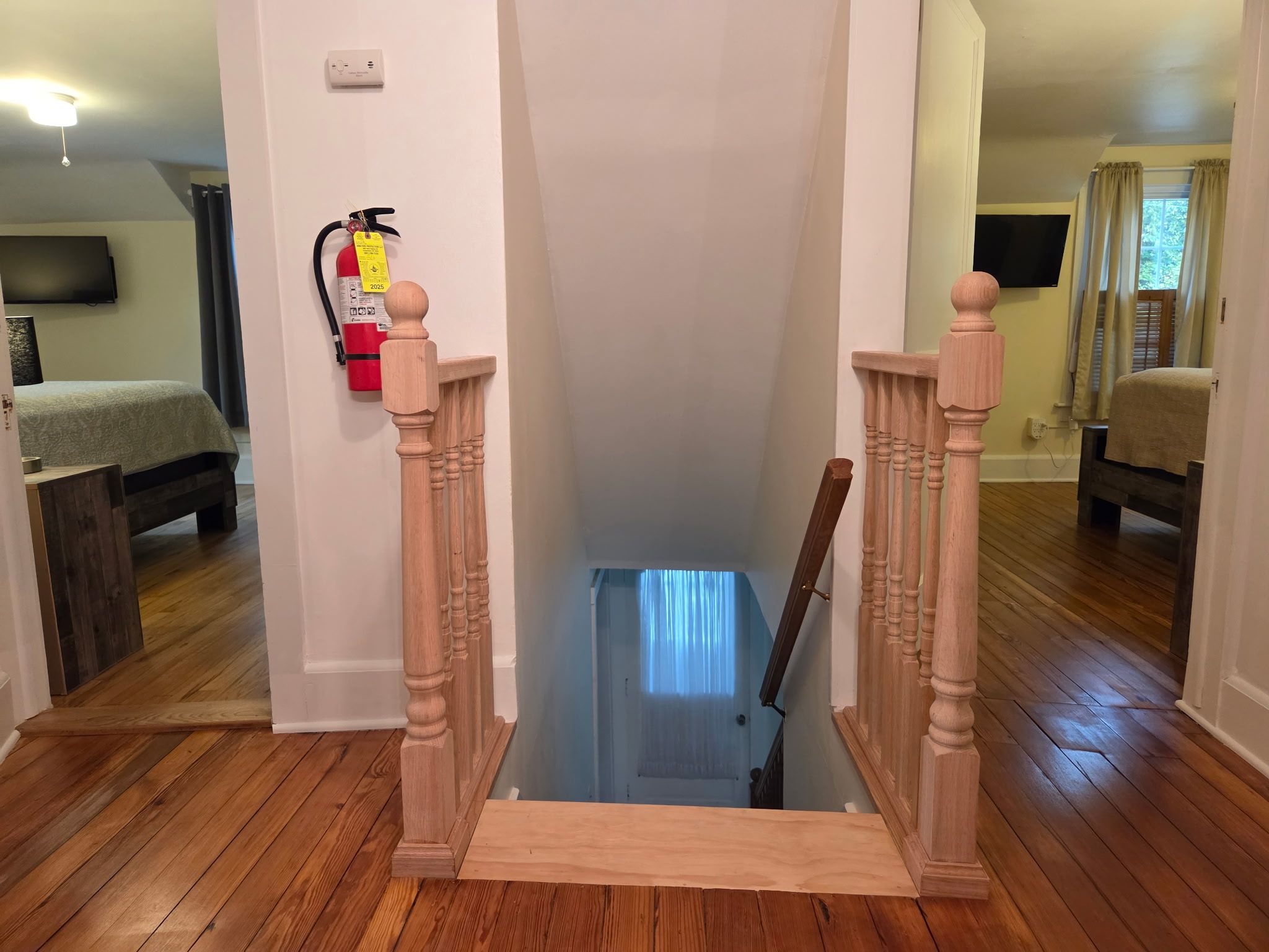 A narrow stairway with wooden railings and a fire extinguisher mounted on the wall.