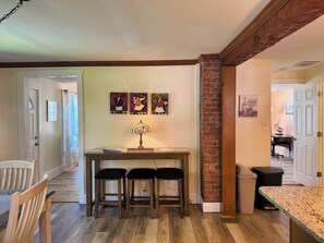 A dining area with a wooden table and three chairs, a lamp, and a 'Welcome to our home' sign. - Beau Rivage Waterfront, kayak, SUP, great fishing, swimming, fire pit, updated (Portlandville)