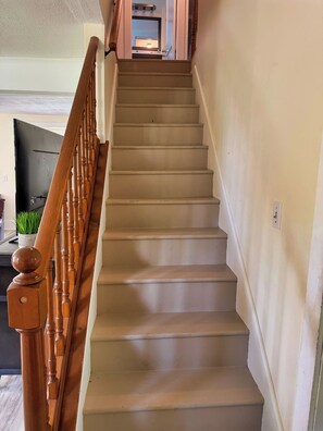 A staircase with wooden balusters and a handrail, leading to an upper floor. - Beau Rivage Waterfront, kayak, SUP, great fishing, swimming, fire pit, updated (Portlandville)