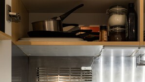Una tetera de acero inoxidable sobre una encimera de cocina moderna, un especiero con frascos y un portalapices.