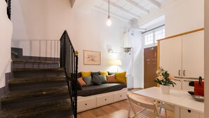 Una escalera que lleva a una cama, una mesita de noche, una lámpara y un ventanal con vistas.