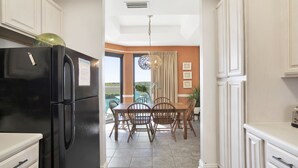 Une cuisine avec un réfrigérateur noir, une table à manger avec des chaises et une vue sur l’extérieur.