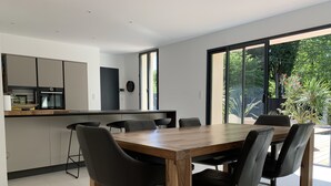 Cocina moderna con mesa de comedor de madera y sillas negras, ventanas amplias y vistas a zonas verdes.