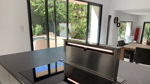 Una cocina moderna con una encimera negra elegante, horno empotrado y vistas al jardín exterior a través de amplios ventanales.