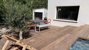 Una terraza de madera con piscina, una mesa y sillas.