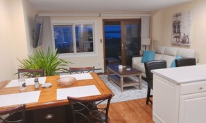 A compact living space with a dining area, a sofa, and a view of the outdoors. - SPECTACULAR OCEAN VIEW BEACHFRONT RENOVATED 2BR (Highlands)