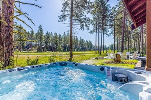 Unwind in a serene hot tub surrounded by a lush landscape and a wooden deck with seating.