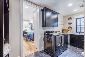 Modern kitchen with washer and dryer, light-colored floor, and a window for natural light.