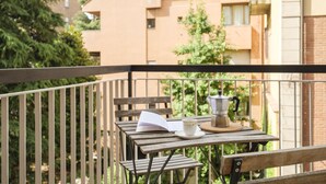 A balcony with a wooden table, a chair, a book, a cup, and a coffee pot. - San Pietro House by Studio Vita (Bologna)