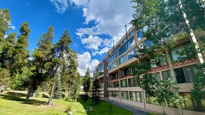 Un bâtiment moderne à plusieurs étages, entouré d’un espace verdoyant bien entretenu, agrémenté d’arbres.