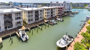 A marina with docked boats, a wooden pier, and multi-story buildings with balconies.