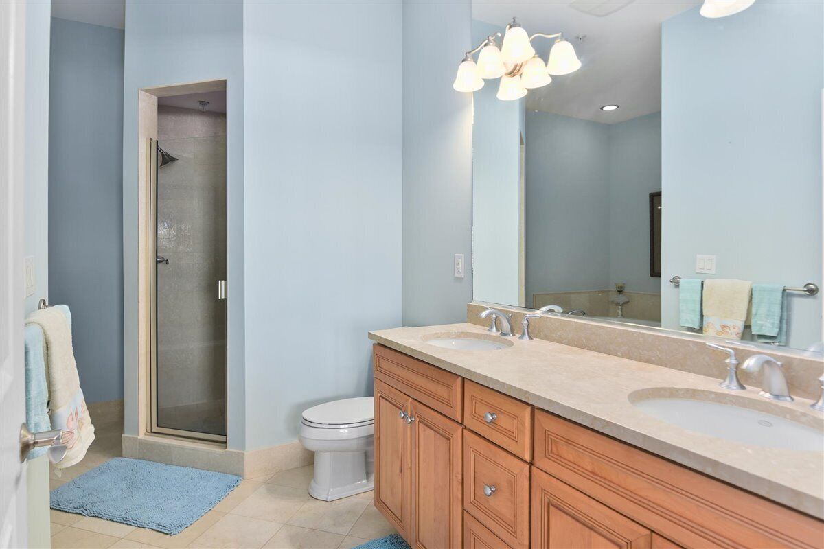 A bathroom with a shower, toilet, double sinks, and a large mirror.