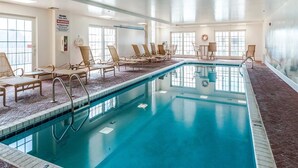 A large indoor swimming pool with multiple lounge chairs and a warning sign on the wall.