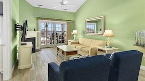 A living room with a green wall, a ceiling fan, a sofa, a coffee table, and a fireplace.