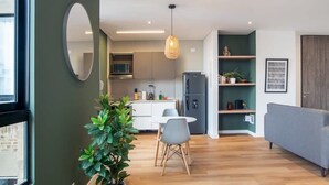 A modern kitchen with a dining area, a grey sofa, and a large window.