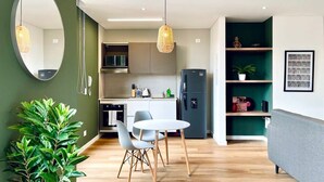 A modern kitchen with a dining area, a large mirror, and a green plant.
