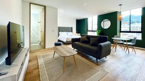 A modern living room with a sofa, coffee table, TV, and a dining area with chairs.