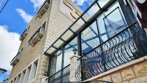 A hotel with a stone facade, large windows, and a balcony with wrought iron railings. - Rami Hotel (Falougha-Khalouat)