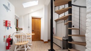 Una cocina moderna con una mesa y sillas de madera, una escalera espiral integrada y un extintor en la pared.