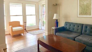 A living room with a blue sofa, a wooden coffee table, and a wicker chair.