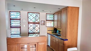 A kitchen with wooden cabinets, a countertop, and a dining area with a table and chairs.