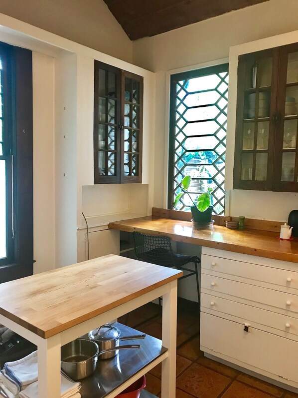 Una cocina con encimera de madera, pileta, estufa y alacenas.