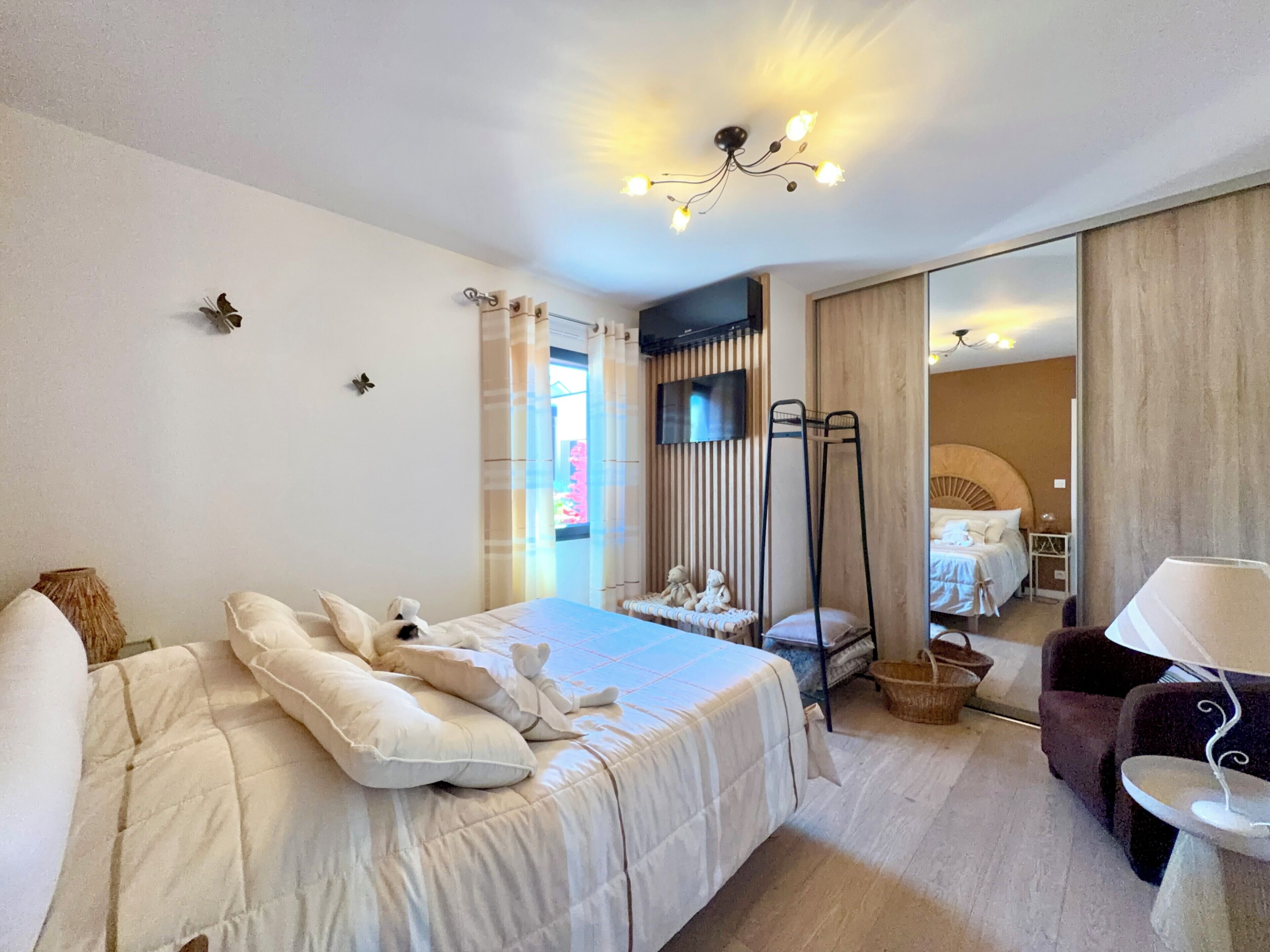 Une chambre d’hôtel avec un lit, une chaise, une table, un téléviseur et un miroir.