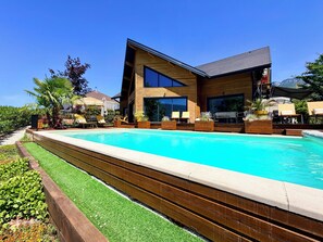A modern house with a swimming pool, wooden deck, and outdoor seating. - Magnificent villa with heated pool air conditioning (Viviers-du-Lac)