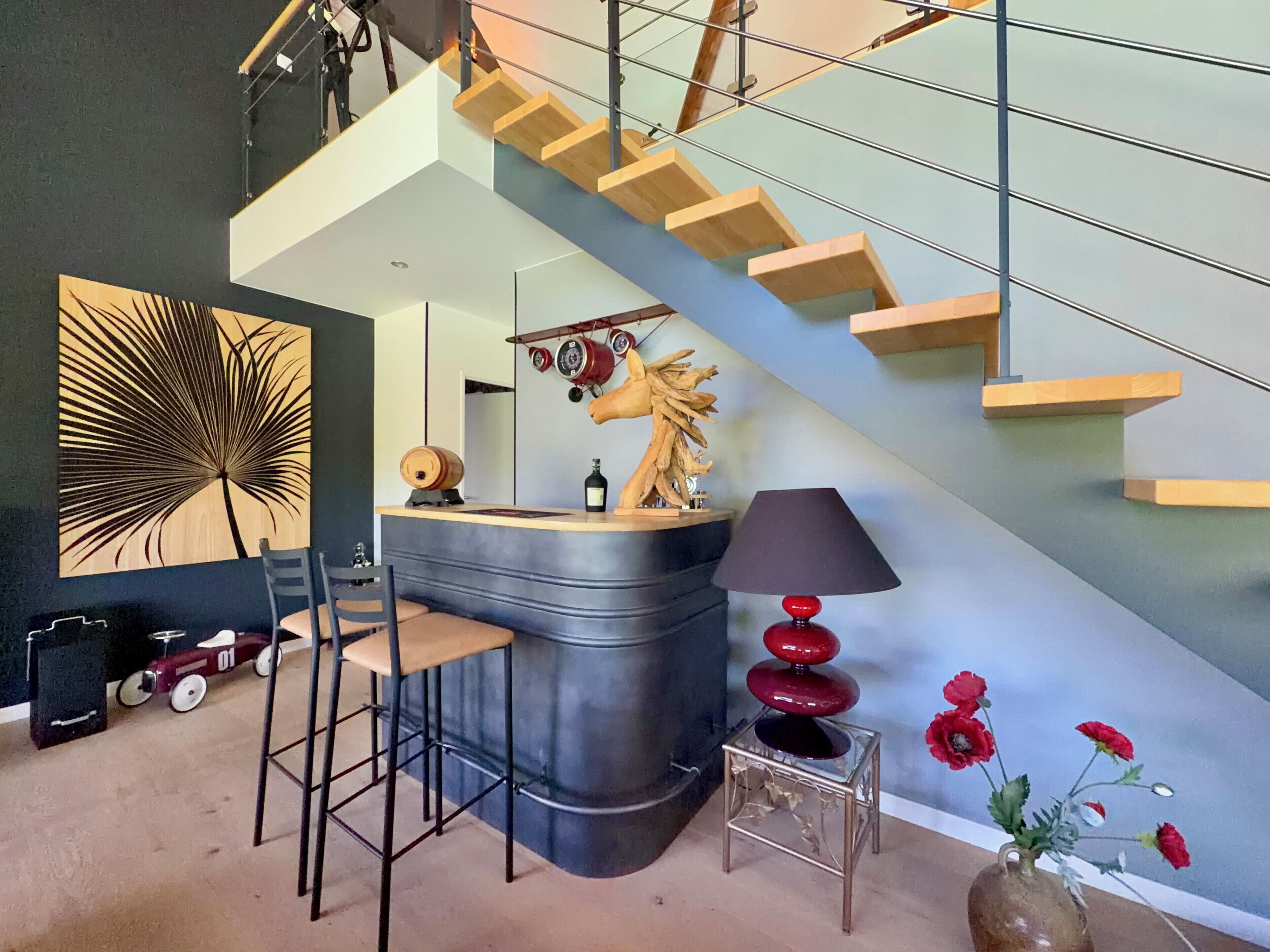 Un interior moderno con una barra curva, una escalera y un elemento decorativo en la pared.