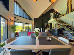 A modern interior with a dining area, a staircase, and a view of the outdoors. - Magnificent villa with heated pool air conditioning (Viviers-du-Lac)