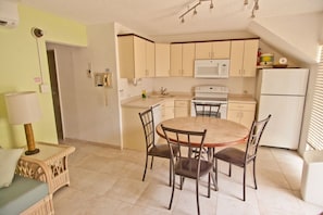 Cozy kitchen with a round dining table and four chairs, featuring a stove, microwave, and refrigerator.