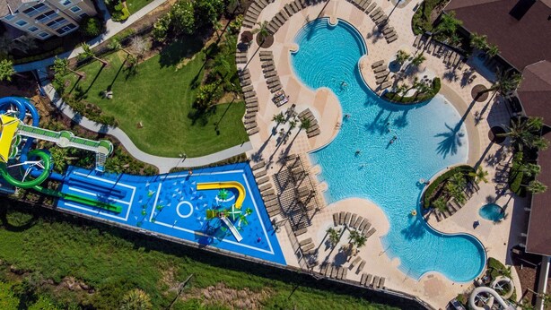 An aerial view of a resort with multiple swimming pools, a water park, and a well-maintained lawn area.