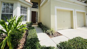 A two-story house with a front entrance, a garage, and a well-maintained garden.