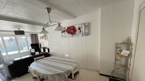 Ein Essbereich mit Tisch und Stühlen, einem Deckenventilator, einem Wanddekor und einem Metallregal mit einer Karte.