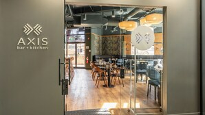 Um interior moderno com bar, cozinha, soalho em madeira e divisórias de vidro.