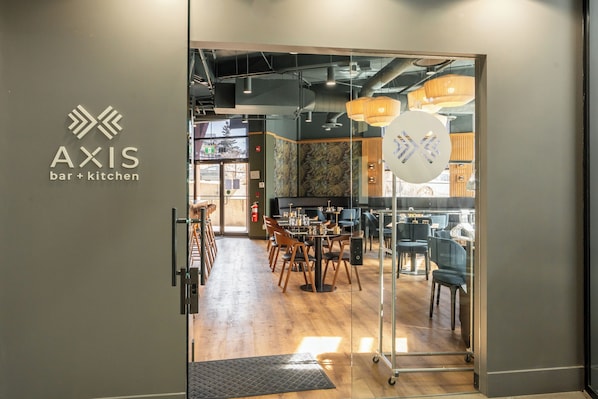 A modern interior with a bar and kitchen area, wooden flooring, and glass partitions.