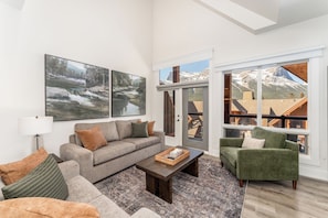 A living room with a sofa, armchair, coffee table, and artwork on the wall.