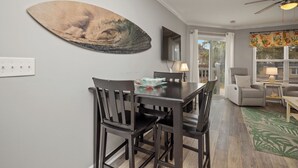 Un espace repas comprenant une table et des chaises, un téléviseur fixé au mur et un ventilateur de plafond.
