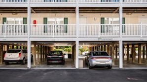Un parking à étages comprenant trois niveaux, chacun étant doté d’une rambarde blanche et de portes numérotées.