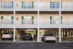 Eine mehrstöckige Parkgarage mit drei Ebenen, jeweils mit weißer Brüstung und nummerierten Türen.