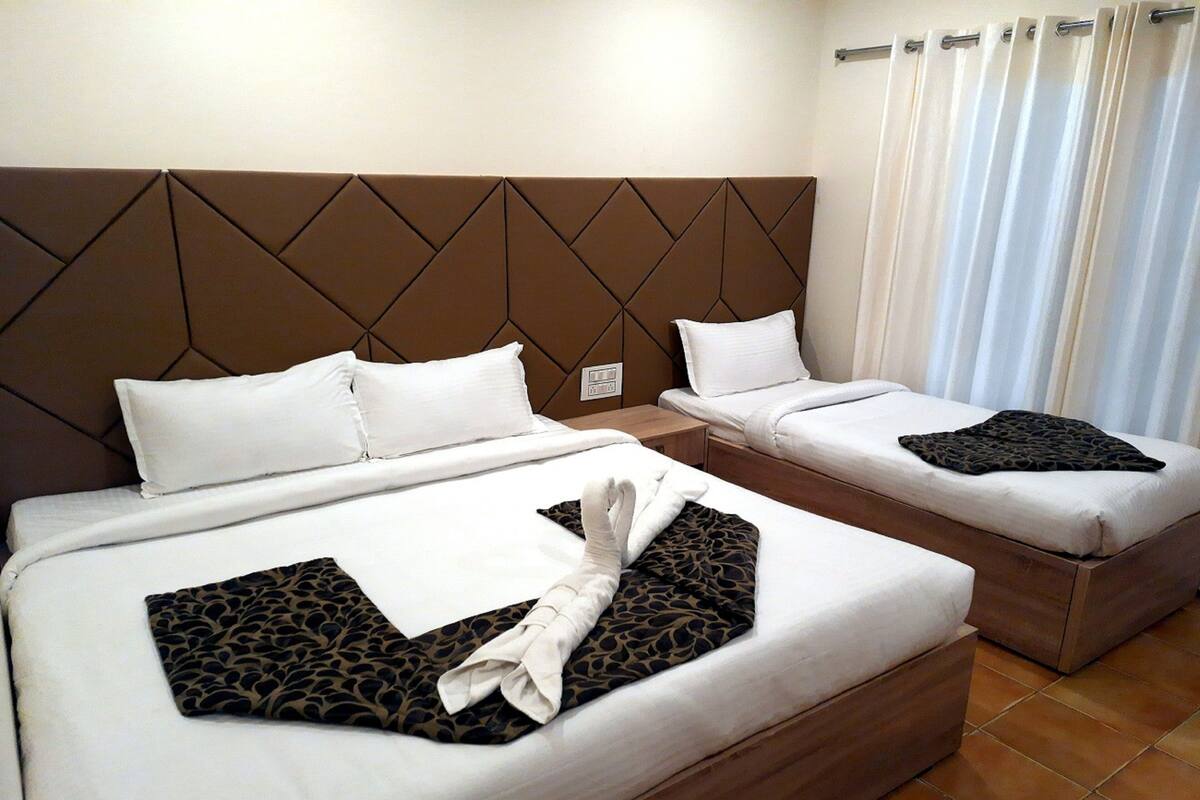 Two beds with headboards, white bedding, and a towel on the beds.