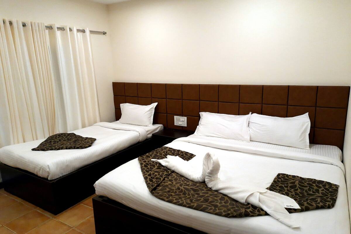 A hotel room with two beds, each with white linens and a brown headboard.