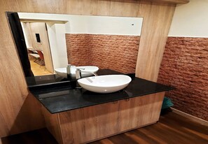 Un baño con tocador de madera, un lavabo blanco y un espejo.