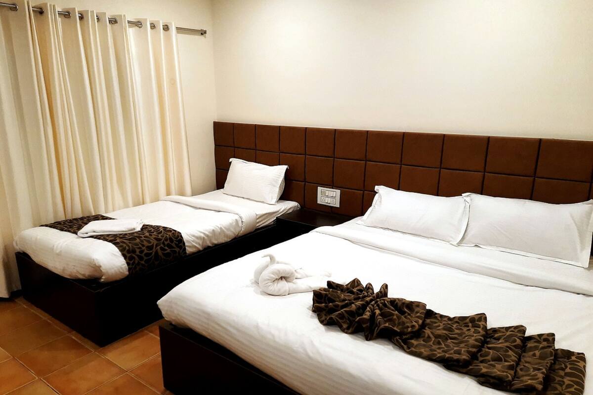 Two twin beds with brown headboards, white bedding, and a brown patterned throw.