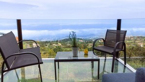 Een balkon met twee stoelen en een tafel, met uitzicht op een schilderachtig landschap.