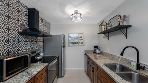 A kitchen with a microwave, stove, refrigerator, and a sink. - 【3 Bedrooms/Firepit/Private Outdoor Dining Area /Local History Themed/Sleep... (Tampa)