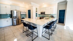 A modern kitchen with a central island, stainless steel appliances, and bar stools. - *Newly Renovated Single Family Home w/Private Pool (Key Colony Beach)