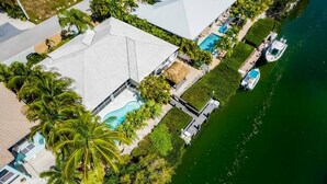 An aerial view of a resort with a swimming pool, docked boats, and lush greenery. - *Newly Renovated Single Family Home w/Private Pool (Key Colony Beach)