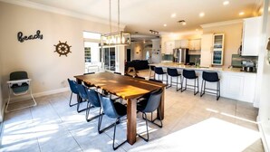 A modern kitchen with a wooden dining table, bar stools, and a kitchen island. - *Newly Renovated Single Family Home w/Private Pool (Key Colony Beach)