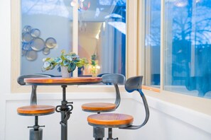 A small, round table with a potted plant on it, surrounded by four wooden chairs with metal legs.